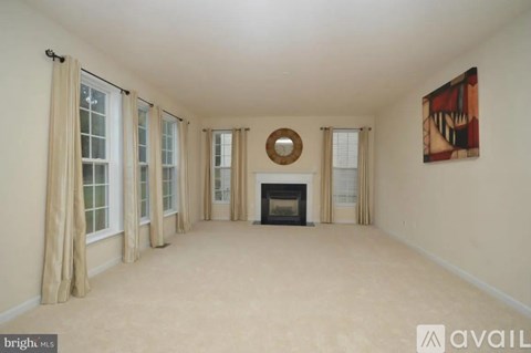 A spacious living room with a fireplace and a painting on the wall.