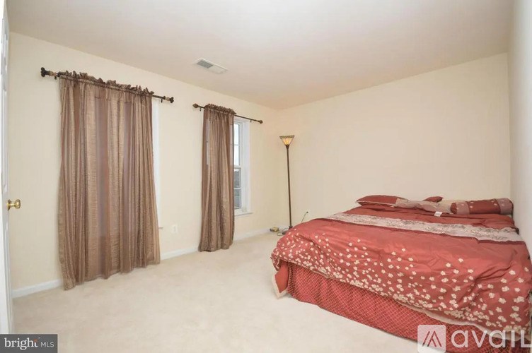 A bedroom with a bed, curtains, and a lamp.