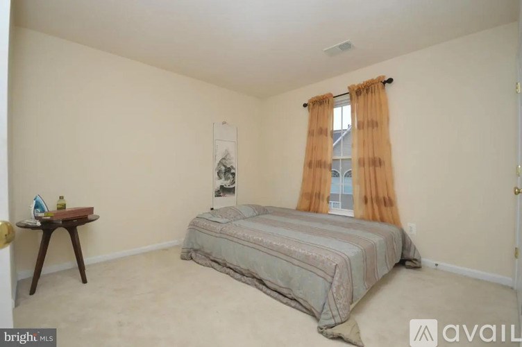 A bedroom with a bed, a table, and a poster on the wall.