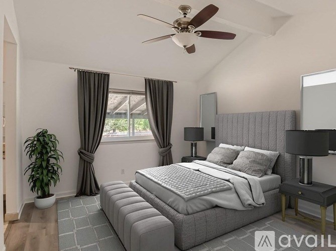 A bedroom with a large bed, a ceiling fan, and a potted plant.