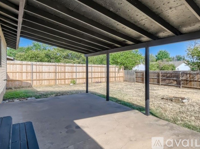 A covered patio area with a bench and a fence in the background.