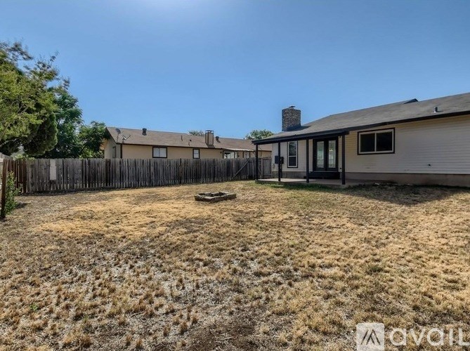 A backyard with a fence and a house in the background.