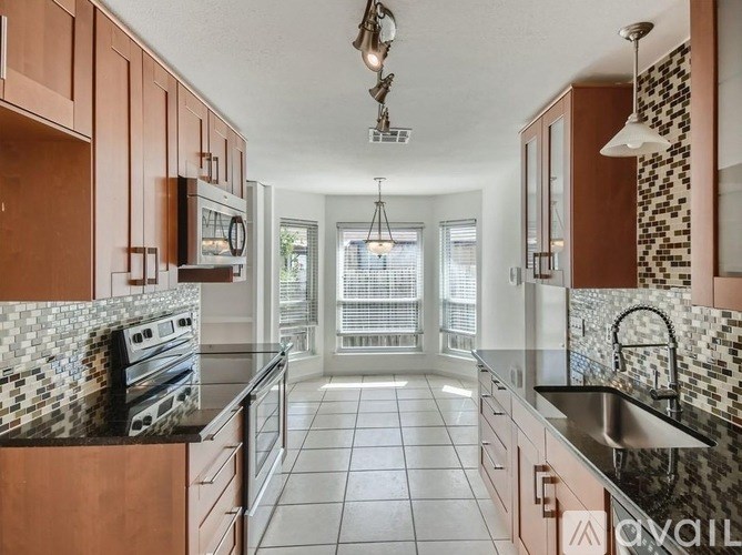 A kitchen with brown cabinets and a black and white tiled backsplash.