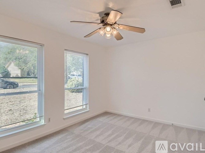 A room with a ceiling fan and two windows.