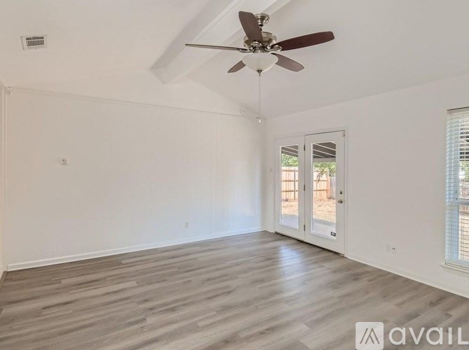 A room with a ceiling fan and wooden flooring.