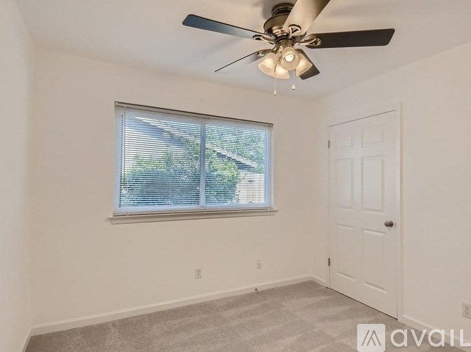 A room with a ceiling fan and a window with blinds.