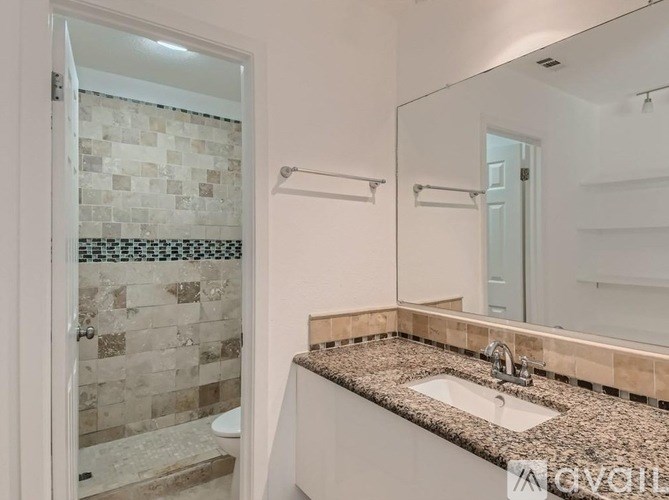 A bathroom with a tiled shower and a granite countertop.
