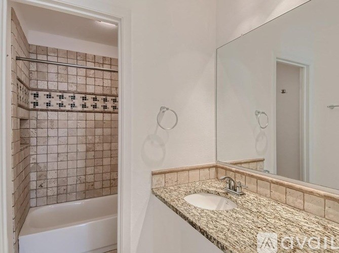 A bathroom with a tiled shower and a granite countertop.