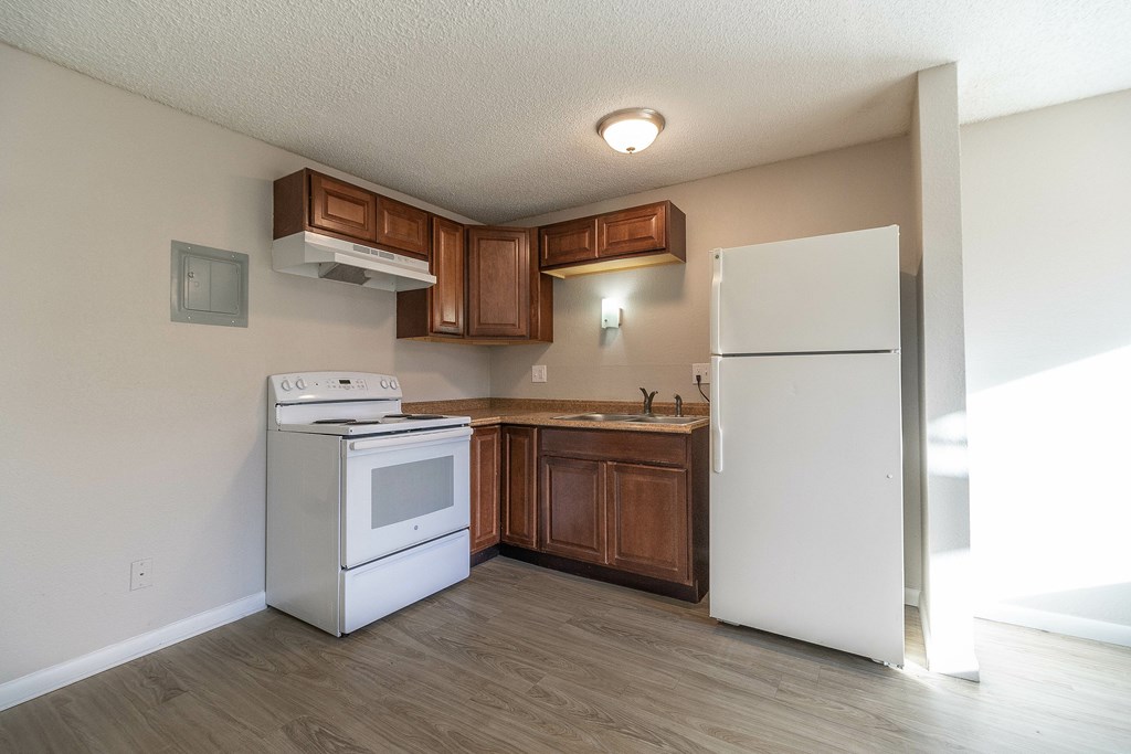 A kitchen with white appliances and wooden cabinets.