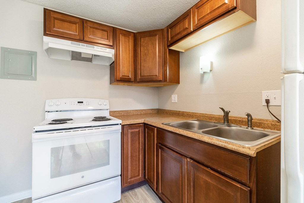 A white stove is in a kitchen with brown cabinets.
