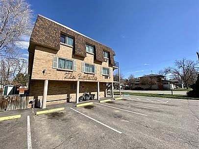 A parking lot in front of a brick building with a motorcycle parked.