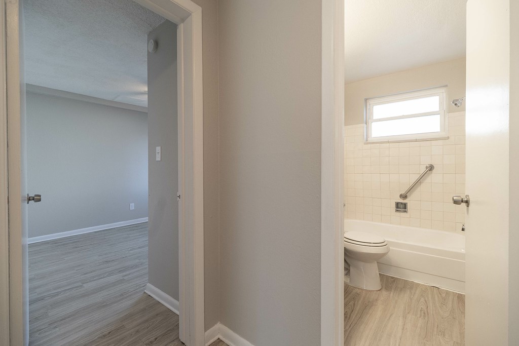 A bathroom with a toilet, tub, and window.