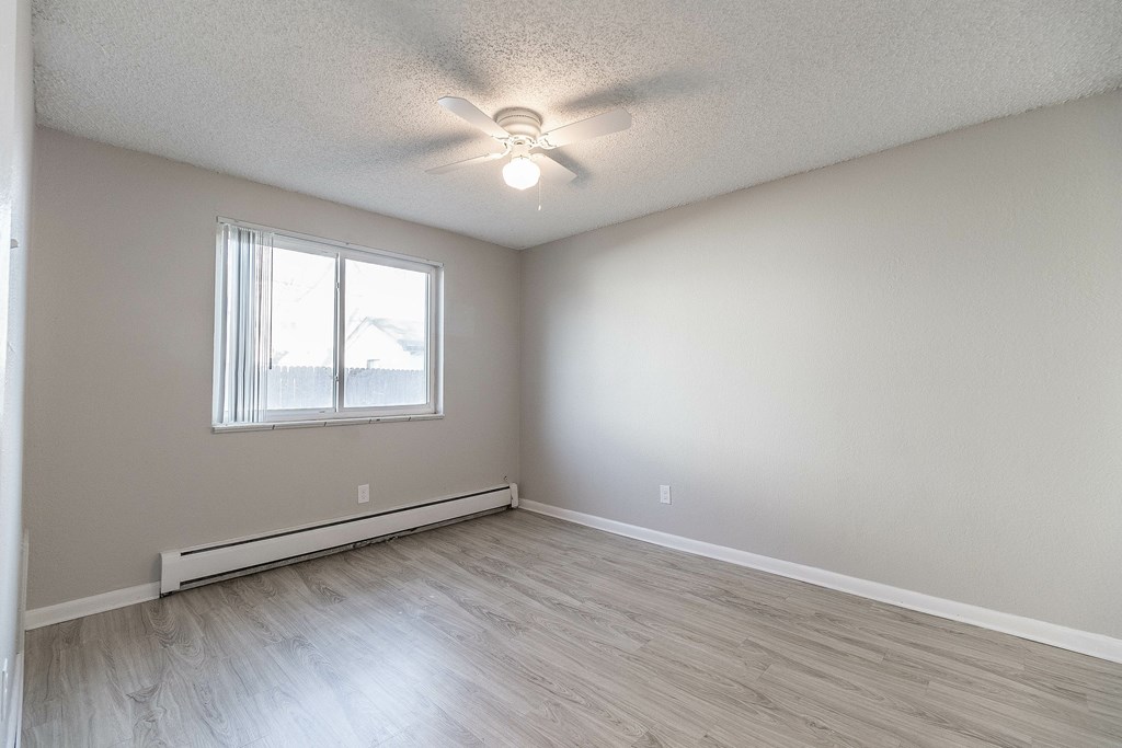 A room with a ceiling fan and a window with blinds.