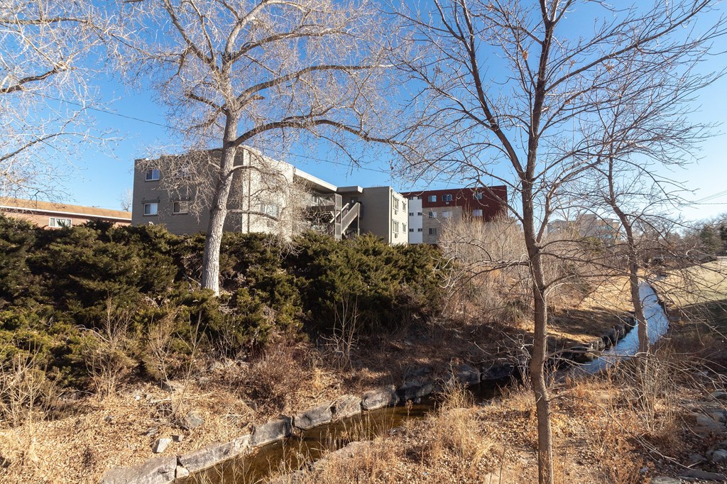 A building is situated on a hill with a small stream running in front of it.