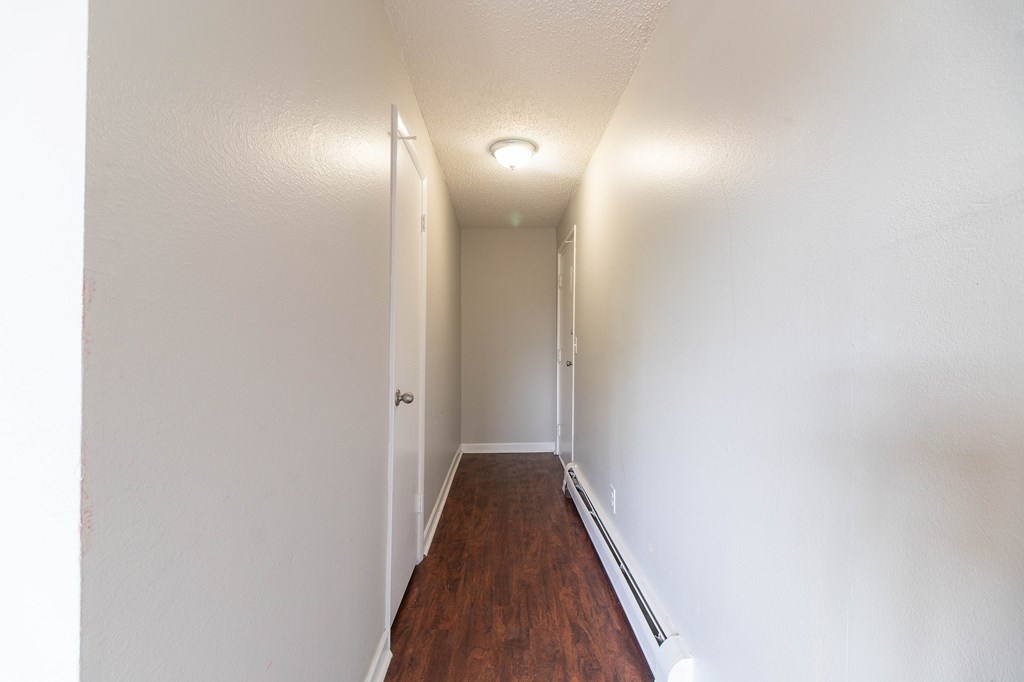 A long hallway with a wooden floor and white walls.