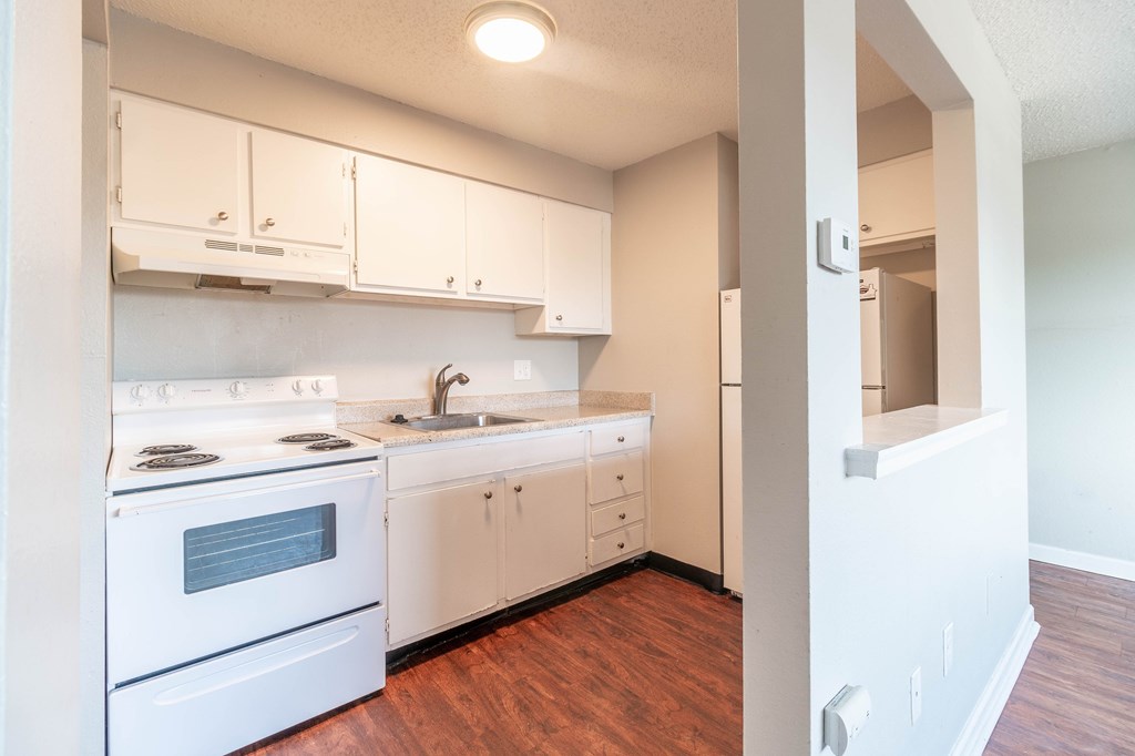 A white kitchen with wood floors and white cabinets.
