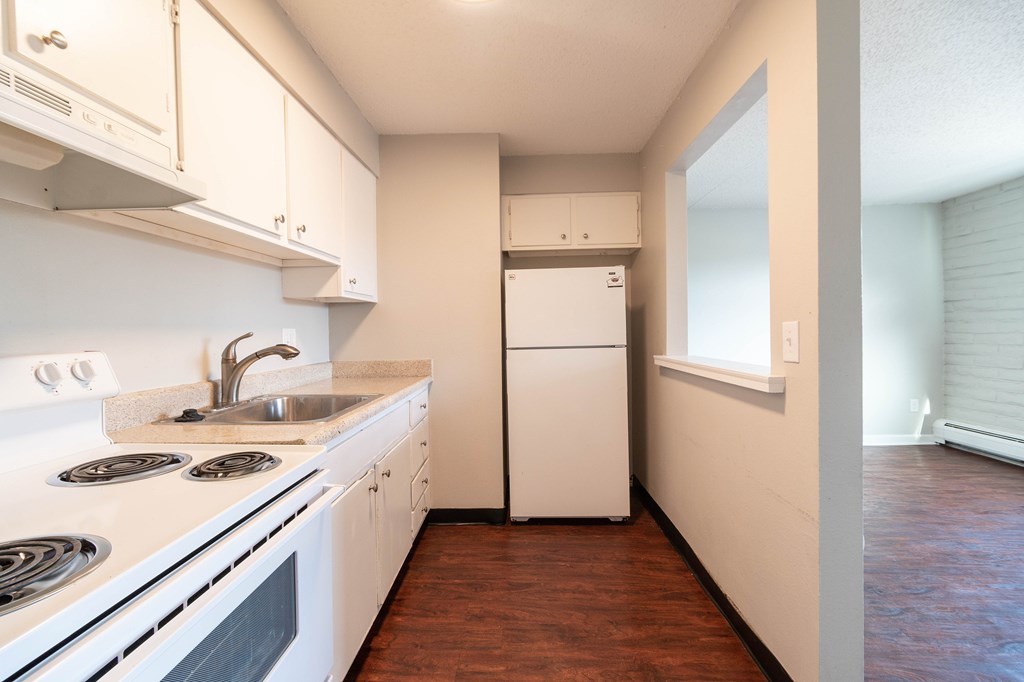 A kitchen with white appliances and wooden floors.