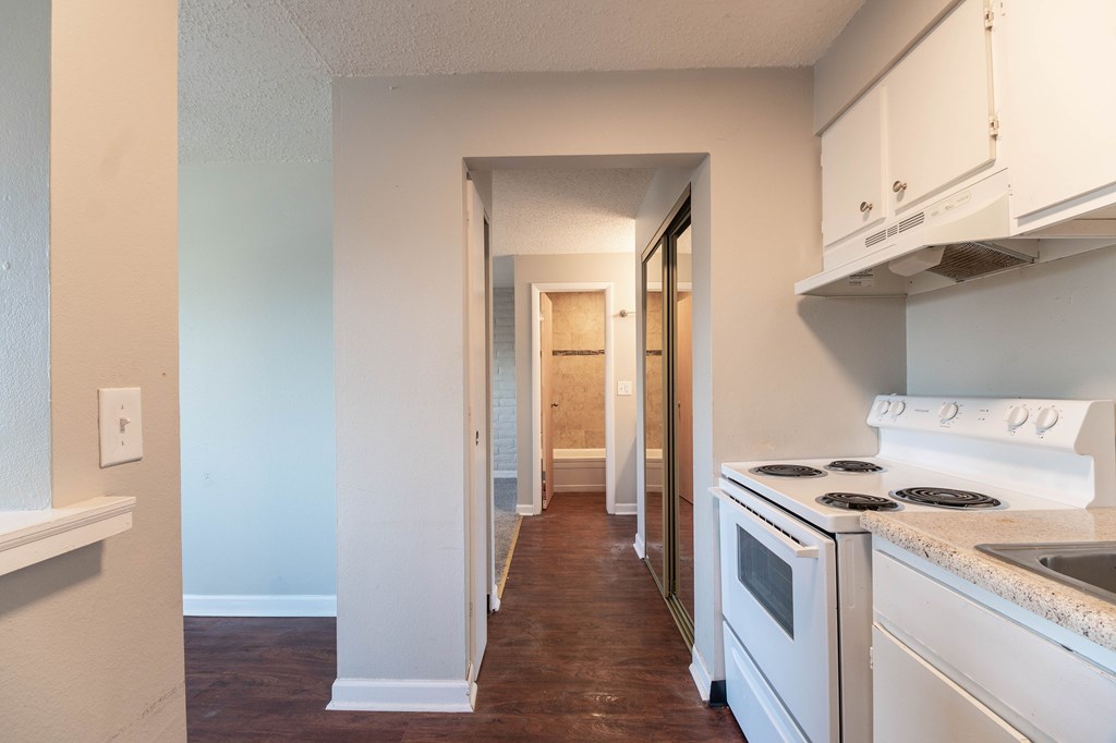 A kitchen with white appliances and wooden floors.