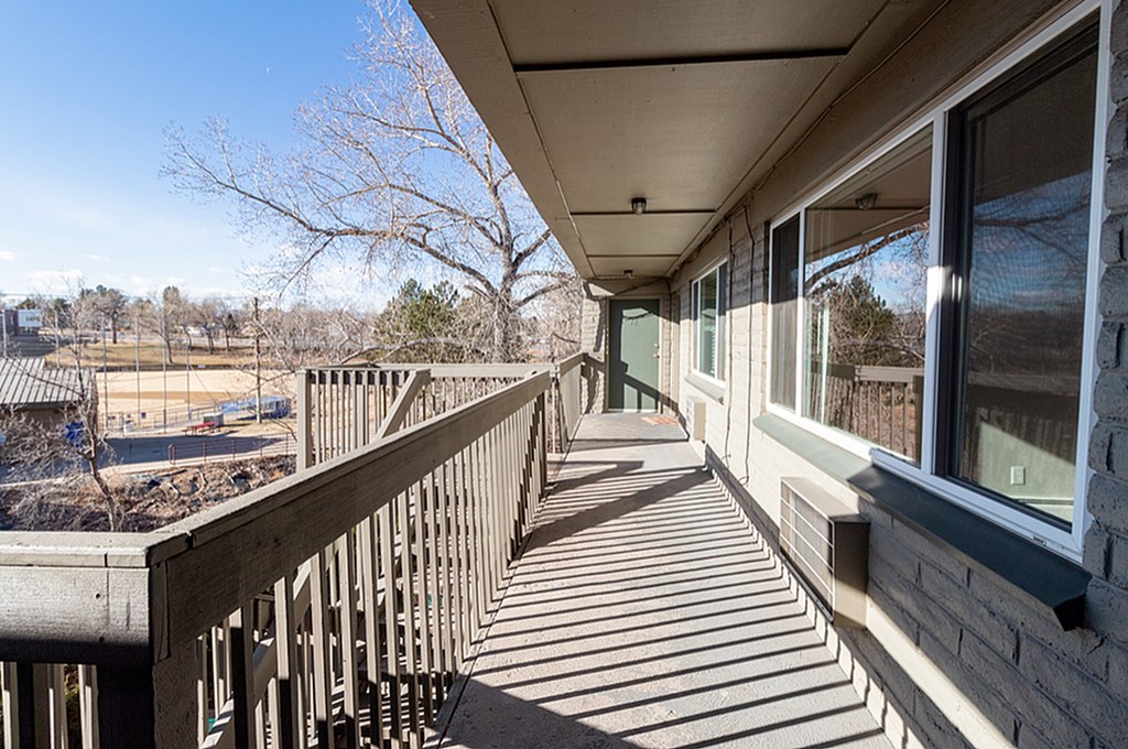 A wooden deck with a railing and a view of a playground.