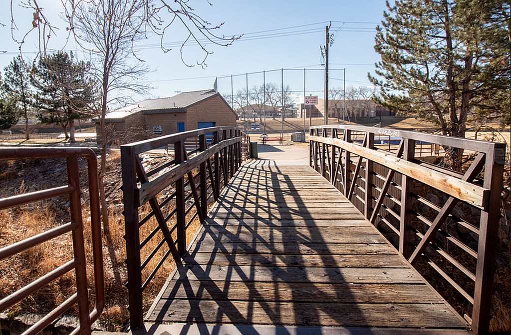 A wooden bridge with metal railings leads to a building.