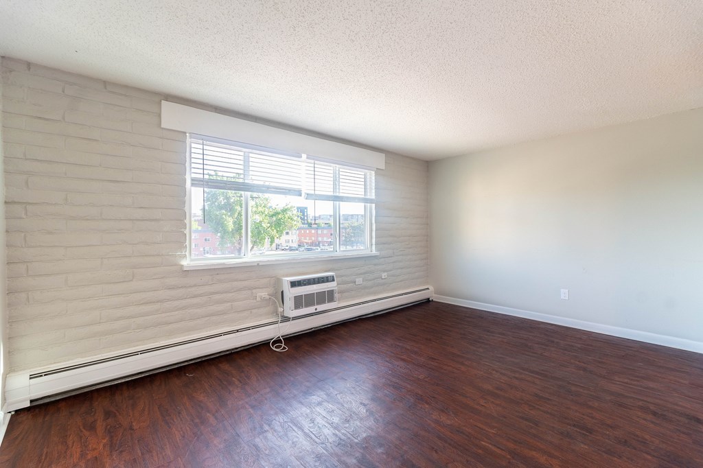 A room with a window covered by blinds and a wall-mounted air conditioner.