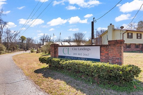 A swimming pool in front of a brick building with trees in the background.