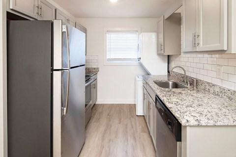 A kitchen with a black refrigerator and a sink.