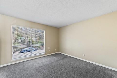 A room with a window showing a blue car and trees outside.