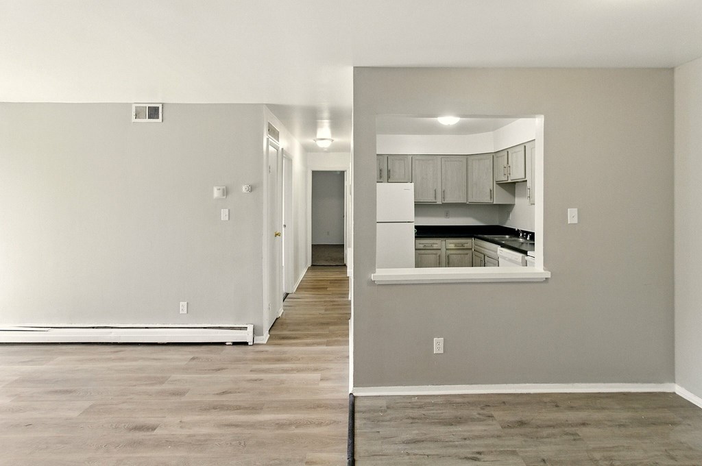 A kitchen area with a white refrigerator and wooden flooring.
