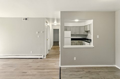 A kitchen area with a white refrigerator and wooden flooring.