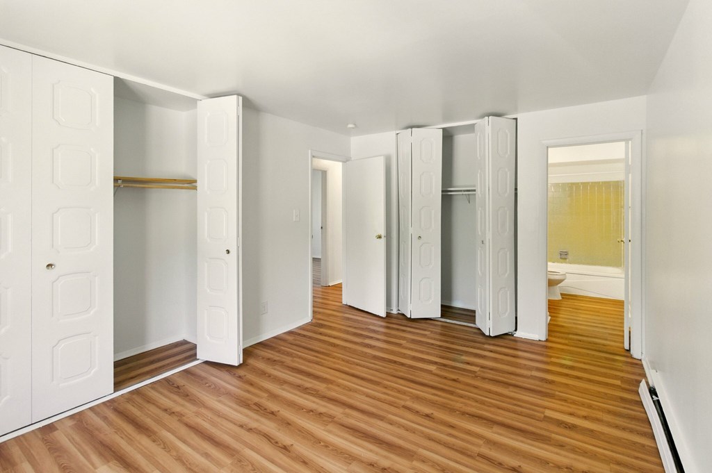 A room with white walls and wooden floors with a white wardrobe.
