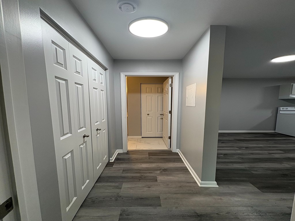 A hallway with a light on the ceiling and a door at the end.