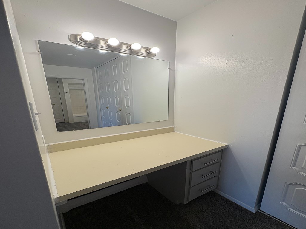 A vanity with a mirror and lights above it.