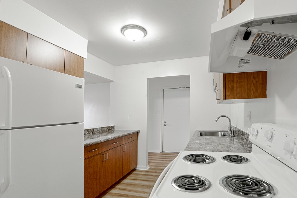 A kitchen with a white fridge, stove, and cabinets.