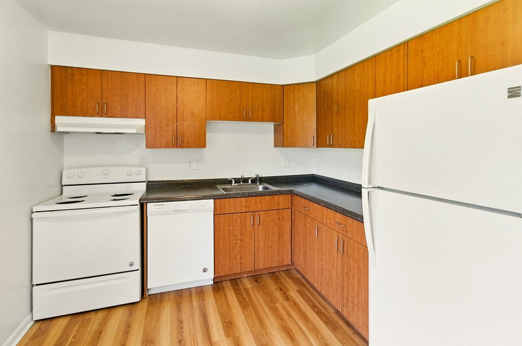A kitchen area with a refrigerator, sink, and cabinets.