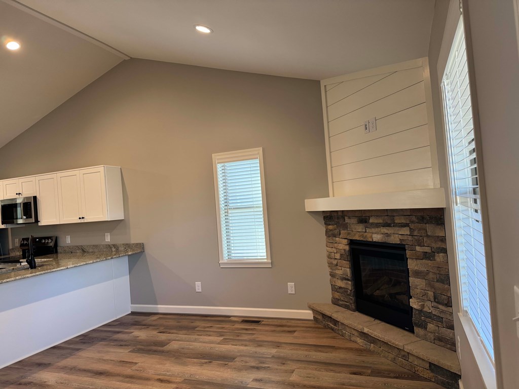 A room with a stone fireplace and wooden floors.