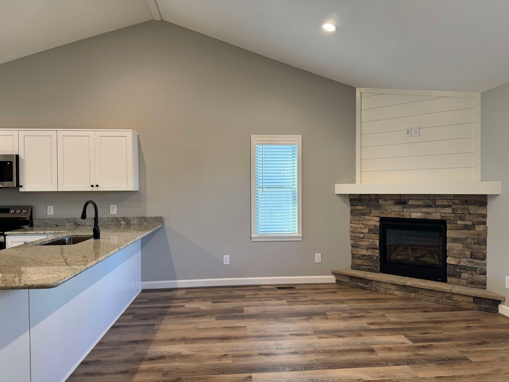 A kitchen with a stone fireplace and wooden floors.