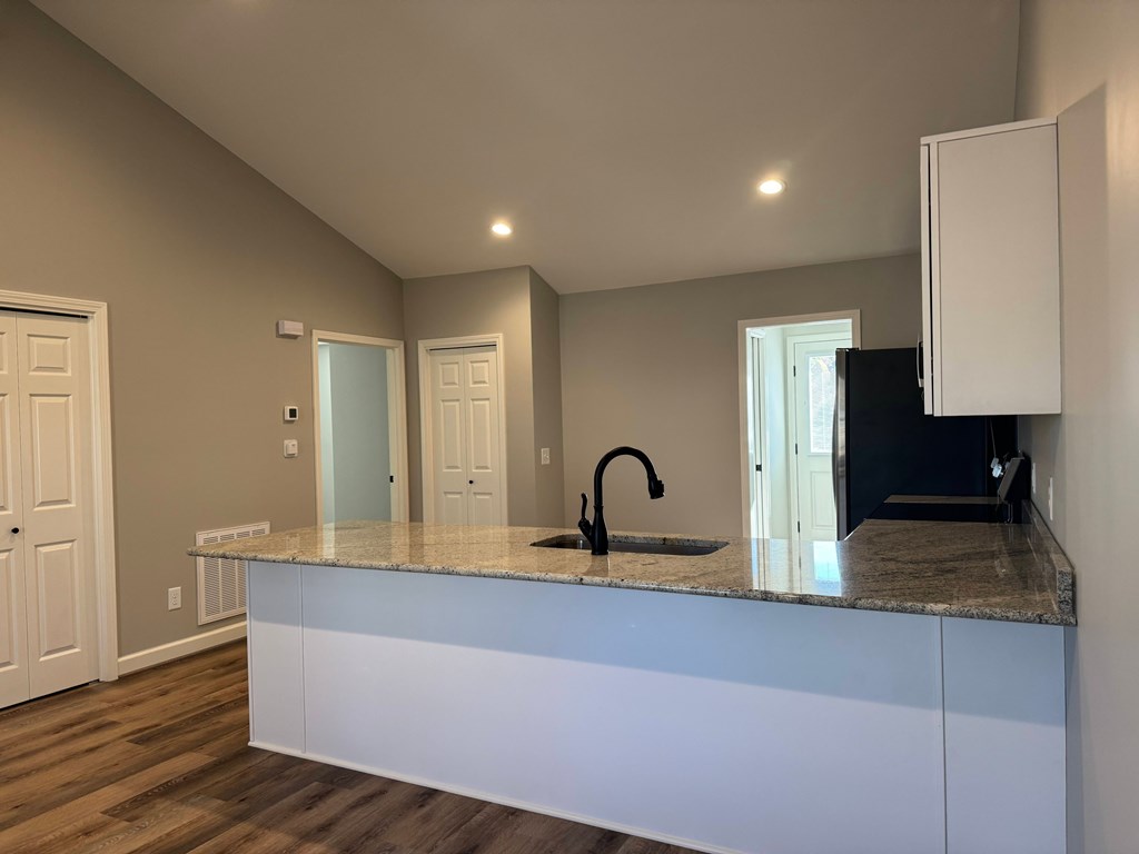 A kitchen with a granite countertop and white cabinets.