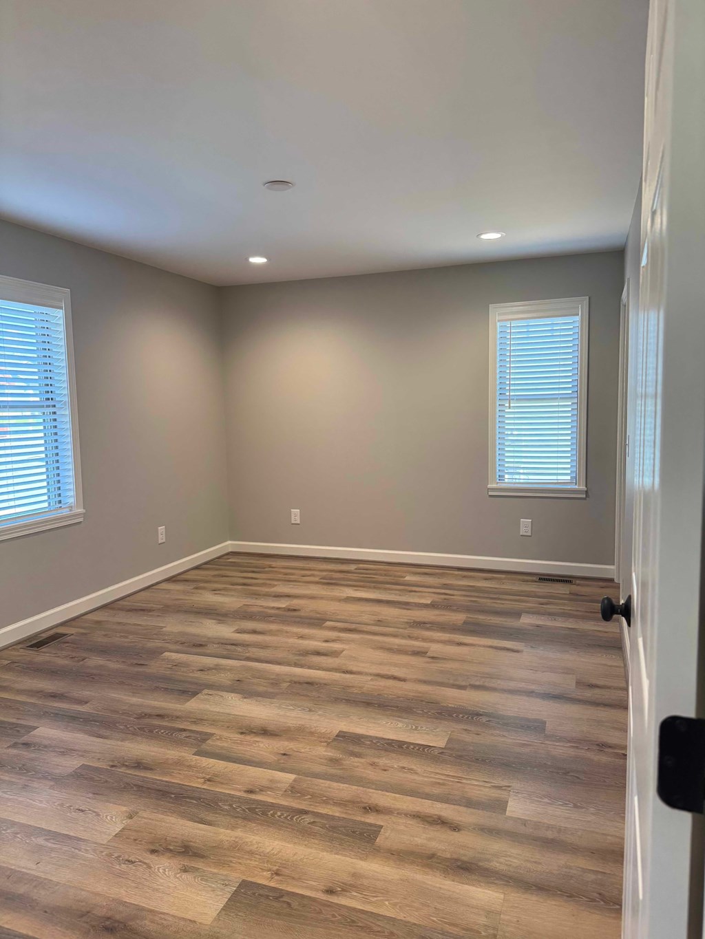 A room with wooden flooring and a window with blinds.
