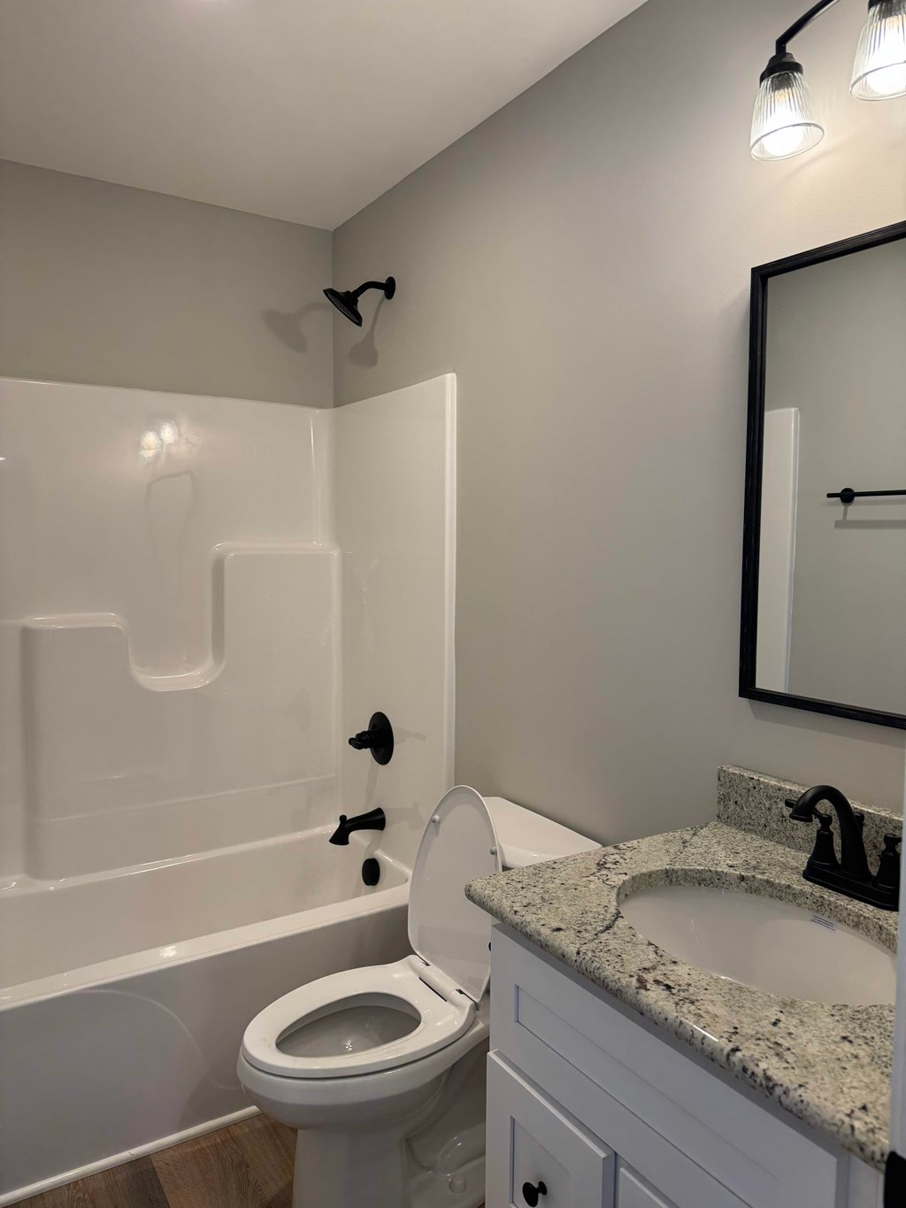 A white toilet with a white bathtub and a marble counter top.