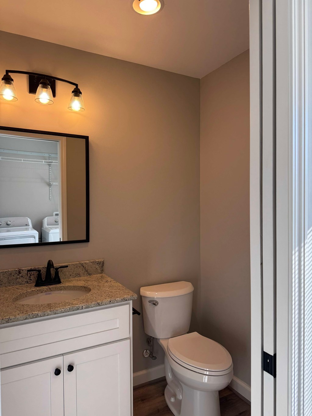A white toilet sits in a bathroom next to a sink and a mirror.