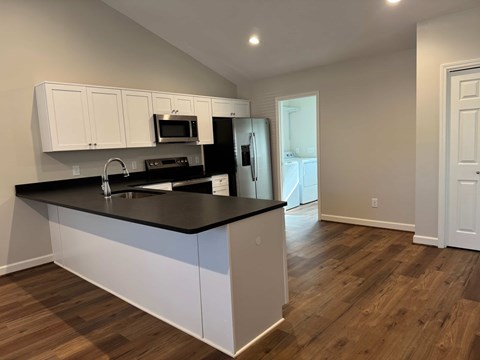 A kitchen with white cabinets and black countertops.