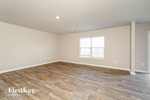 A room with wooden flooring and a window with blinds.