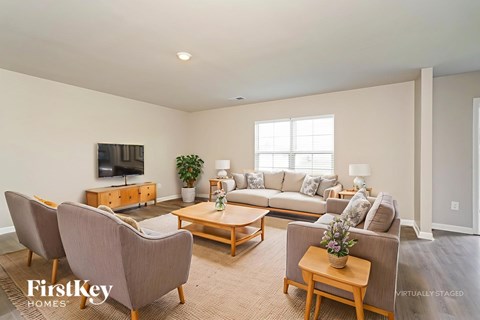A living room with a couch, chairs, and a television.