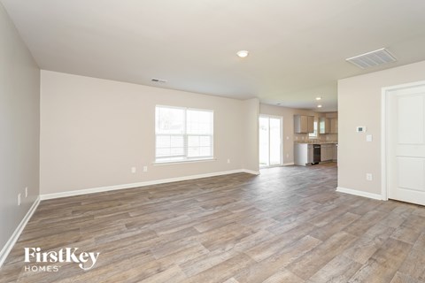 A spacious room with wooden flooring and a large window.