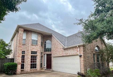 A two-story house with a brick facade and a white garage door.