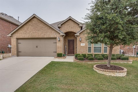 A house with a brown garage door and a tree in front.