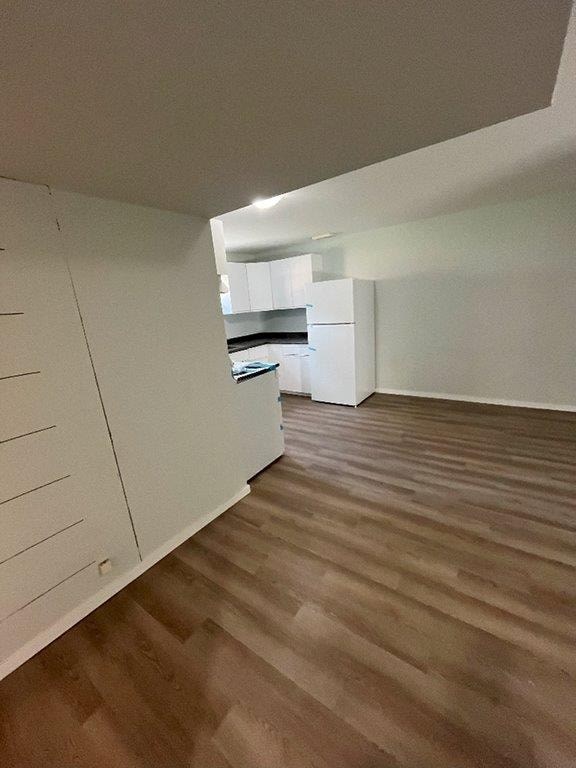 A kitchen with white cabinets and a wooden floor.