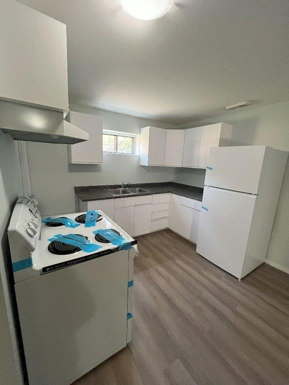 A white kitchen with a stove top oven and a refrigerator.