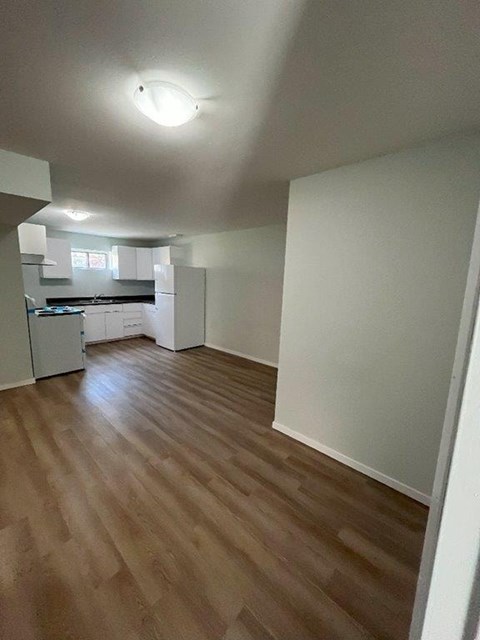 A kitchen with white cabinets and a wooden floor.